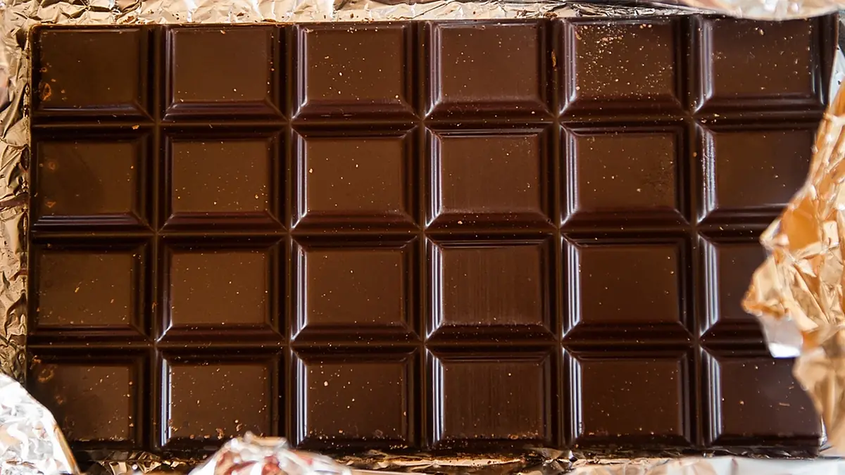 Barra de chocolate amargo em quadradinhos, sobre o papel da embalagem