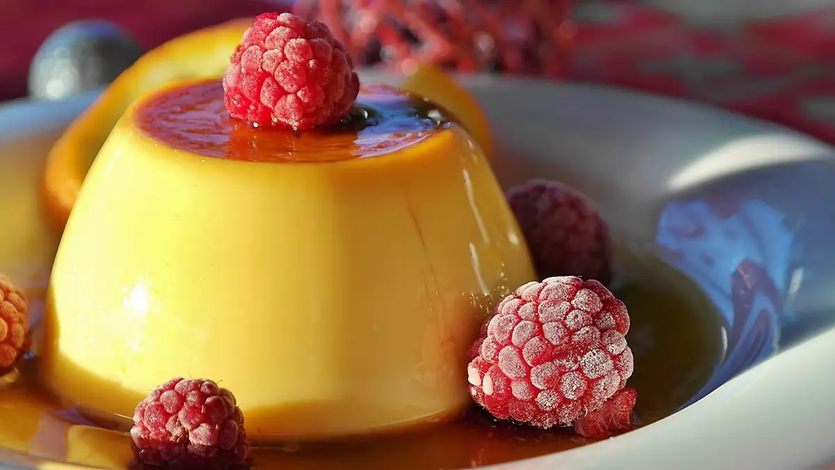 Pudim com calda de caramelo enfeitado com framboesas