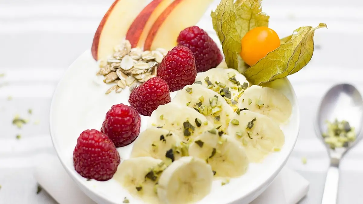 Tigela com banana fatiada, framboesas e frutas, ideia para sorvete de banana